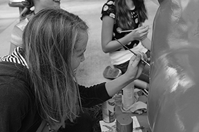Brushing the paint onto the cat sculpture, 
Andrea Turner, eighth grade visual major, paints her design onto the cat along with a few of her friends.
