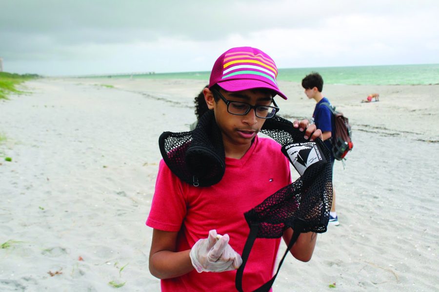 Looking at his discoveries, Samanyu Kodiganti, eighth grade band major helps his community. “It was fun because we were all running around, excited to clean up the beach,” Kodiganti said. Photo by Kya Small-Brush